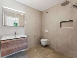 Experience modern luxury in this beautifully appointed bathroom, featuring a sleek vanity with a wooden finish and a spacious sink.