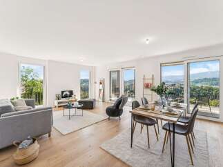 Experience modern living in this spacious open-plan apartment, featuring a comfortable living area with a grey sofa and a stylish dining set perfect for entertaining.