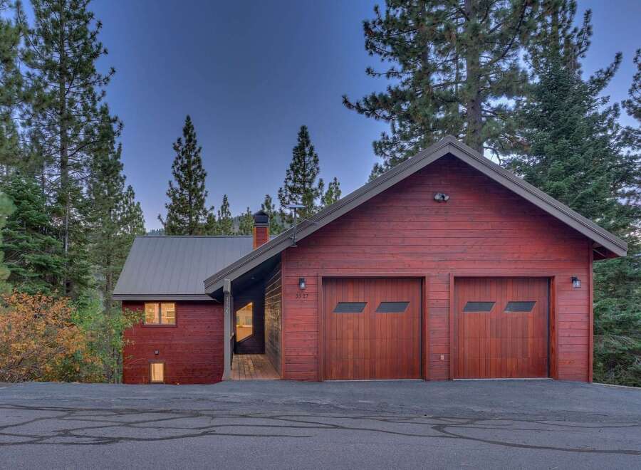 Nestled amidst tall pine trees, this charming red wood-sided home offers a serene mountain retreat.