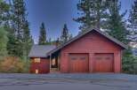 Nestled amidst tall pine trees, this charming red wood-sided home offers a serene mountain retreat.