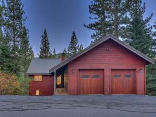 Nestled amidst tall pine trees, this charming red wood-sided home offers a serene mountain retreat.