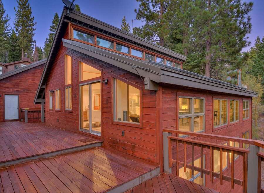This stunning red wooden home is nestled amongst tall pine trees, offering a serene and private retreat.