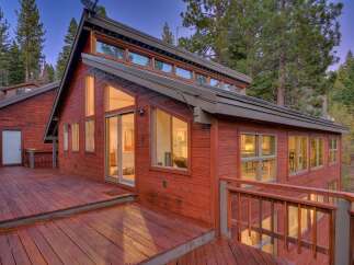 This stunning red wooden home is nestled amongst tall pine trees, offering a serene and private retreat.