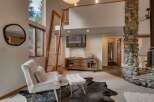 Experience rustic charm in this inviting living space, featuring a towering stone fireplace and a unique wooden ladder leading to a loft.