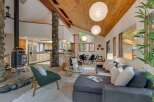 Experience the warmth and natural beauty of this stunning living space, featuring a striking stone-clad fireplace and a vaulted wood-beamed ceiling that creates an airy, open atmosphere.