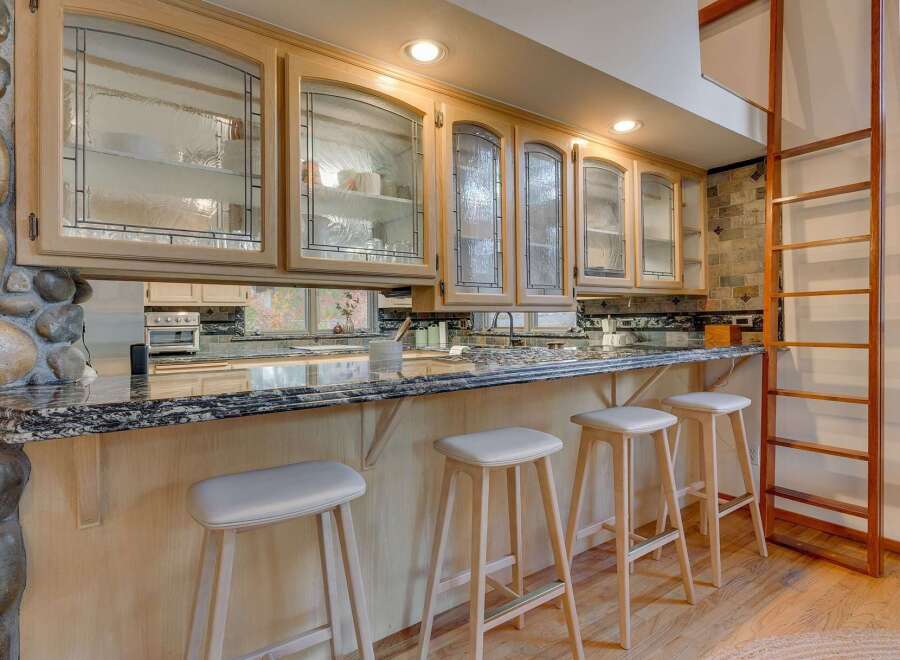 This kitchen boasts custom light wood cabinetry with decorative glass fronts, offering a sophisticated display for dishware.