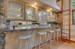 This kitchen boasts custom light wood cabinetry with decorative glass fronts, offering a sophisticated display for dishware.