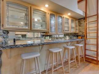 This kitchen boasts custom light wood cabinetry with decorative glass fronts, offering a sophisticated display for dishware.