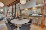 Experience open-concept living with a stunning vaulted wood-beamed ceiling and a striking stone-clad pillar supporting a wood-burning stove.