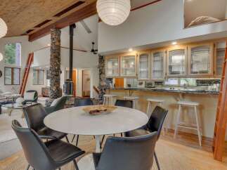 Experience open-concept living with a stunning vaulted wood-beamed ceiling and a striking stone-clad pillar supporting a wood-burning stove.