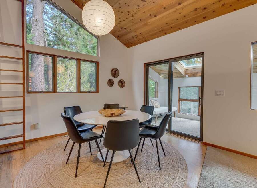 This dining area features a modern white pedestal table surrounded by sleek black chairs, all set on a natural jute rug.