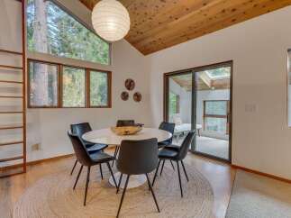 This dining area features a modern white pedestal table surrounded by sleek black chairs, all set on a natural jute rug.