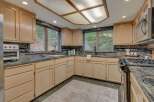 This spacious kitchen boasts light wood cabinetry complemented by dark granite countertops and a decorative tile backsplash.