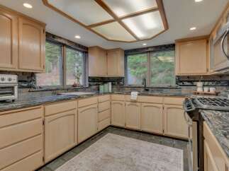 This spacious kitchen boasts light wood cabinetry complemented by dark granite countertops and a decorative tile backsplash.