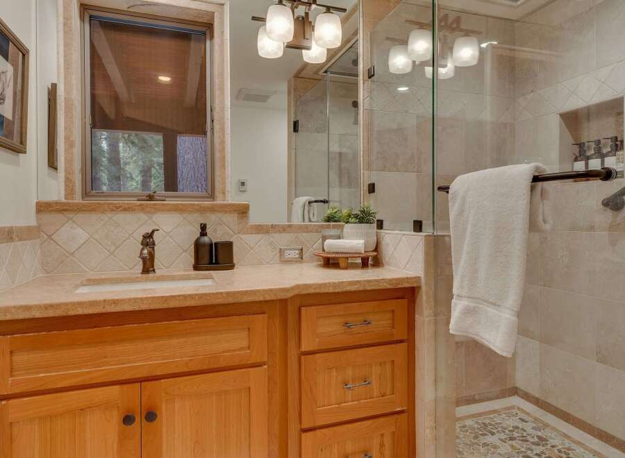This bathroom features a warm and inviting aesthetic with natural wood cabinetry and a stone countertop.