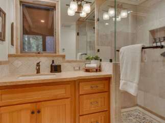This bathroom features a warm and inviting aesthetic with natural wood cabinetry and a stone countertop.