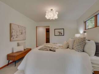 Experience serene comfort in this beautifully appointed bedroom, featuring a plush white duvet and an array of decorative pillows.