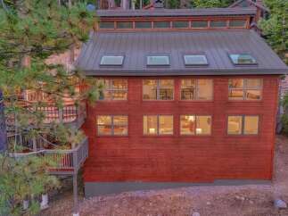 Nestled amongst tall pine trees, this stunning red-sided home offers a unique architectural design with multiple levels of living space.