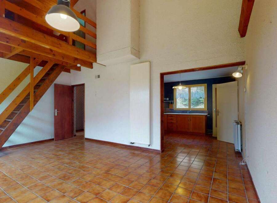 This spacious living area features a striking wooden mezzanine accessible by a charming staircase, offering a unique architectural element.