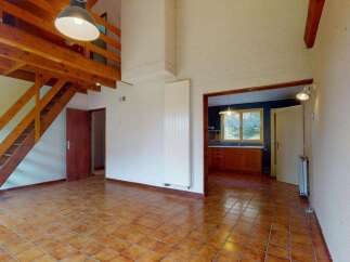 This spacious living area features a striking wooden mezzanine accessible by a charming staircase, offering a unique architectural element.