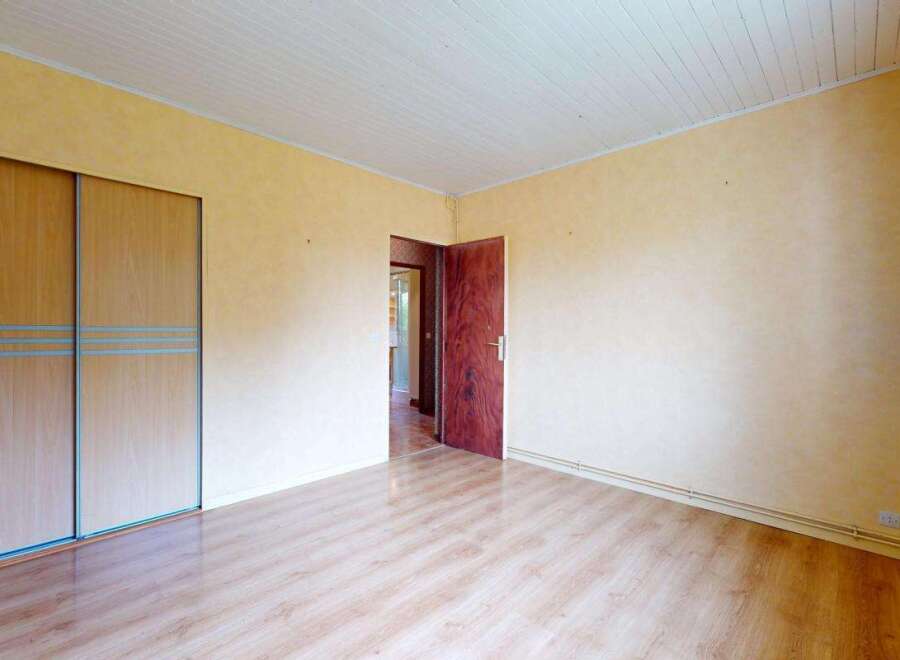 This spacious room features a large built-in wardrobe with light wood sliding doors, offering ample storage solutions.
