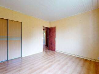 This spacious room features a large built-in wardrobe with light wood sliding doors, offering ample storage solutions.