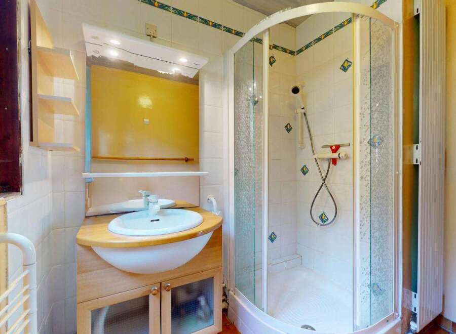 This bathroom features a spacious corner shower with a frosted glass enclosure and decorative tile accents.