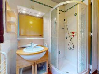 This bathroom features a spacious corner shower with a frosted glass enclosure and decorative tile accents.