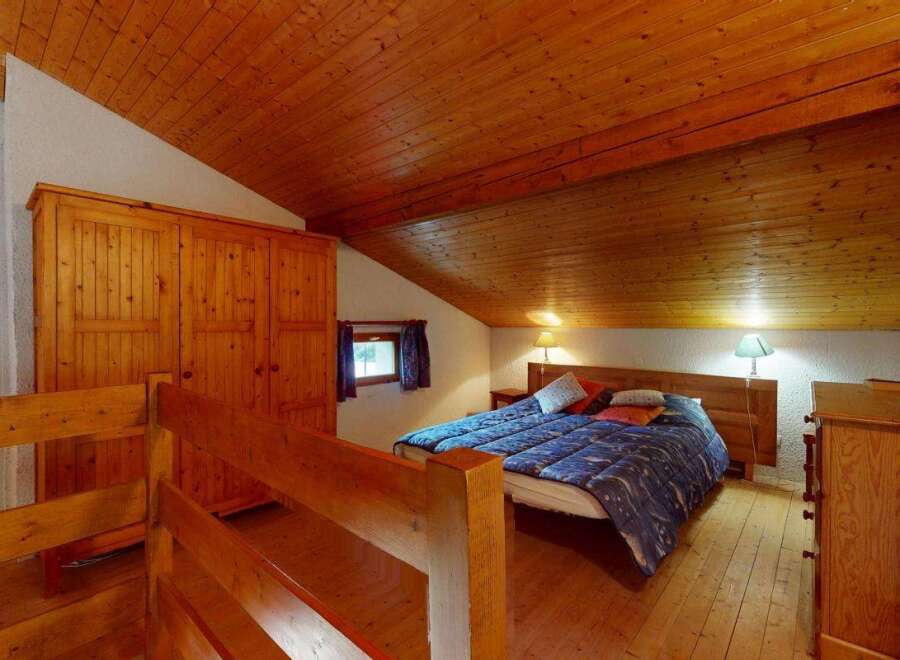 Discover this charming bedroom featuring a cozy bed with a blue patterned comforter and decorative pillows.