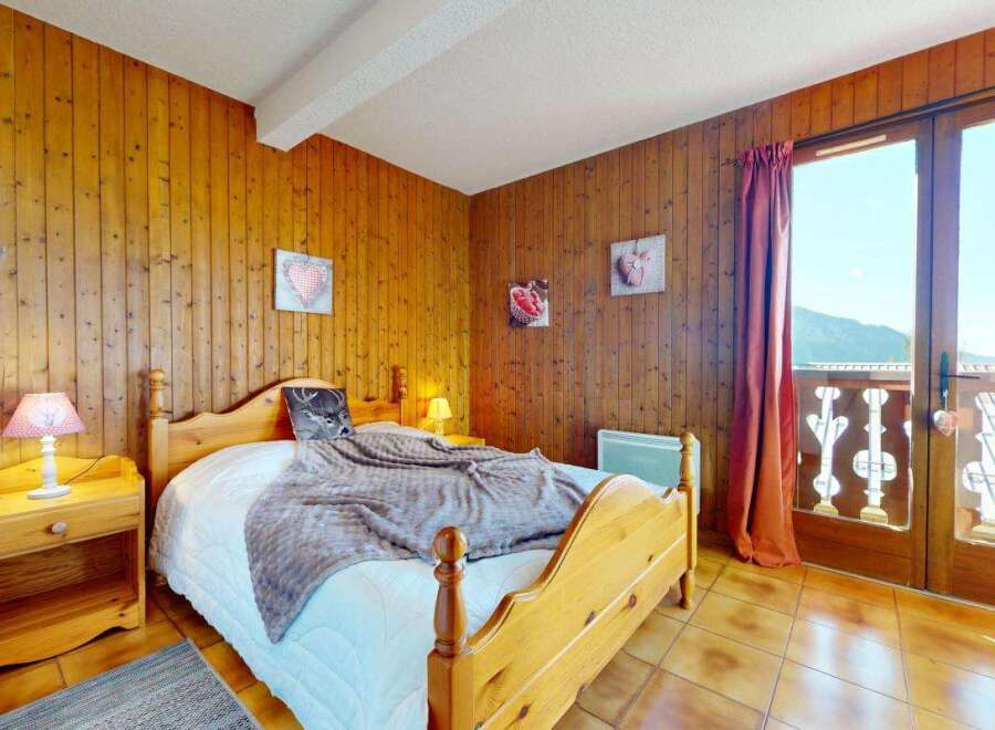 Experience cozy mountain living in this charming bedroom featuring warm wood-paneled walls and a comfortable bed.