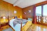 Experience cozy mountain living in this charming bedroom featuring warm wood-paneled walls and a comfortable bed.