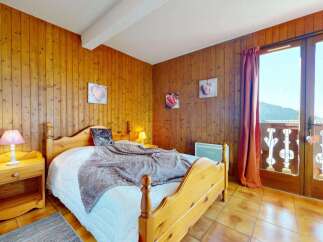 Experience cozy mountain living in this charming bedroom featuring warm wood-paneled walls and a comfortable bed.