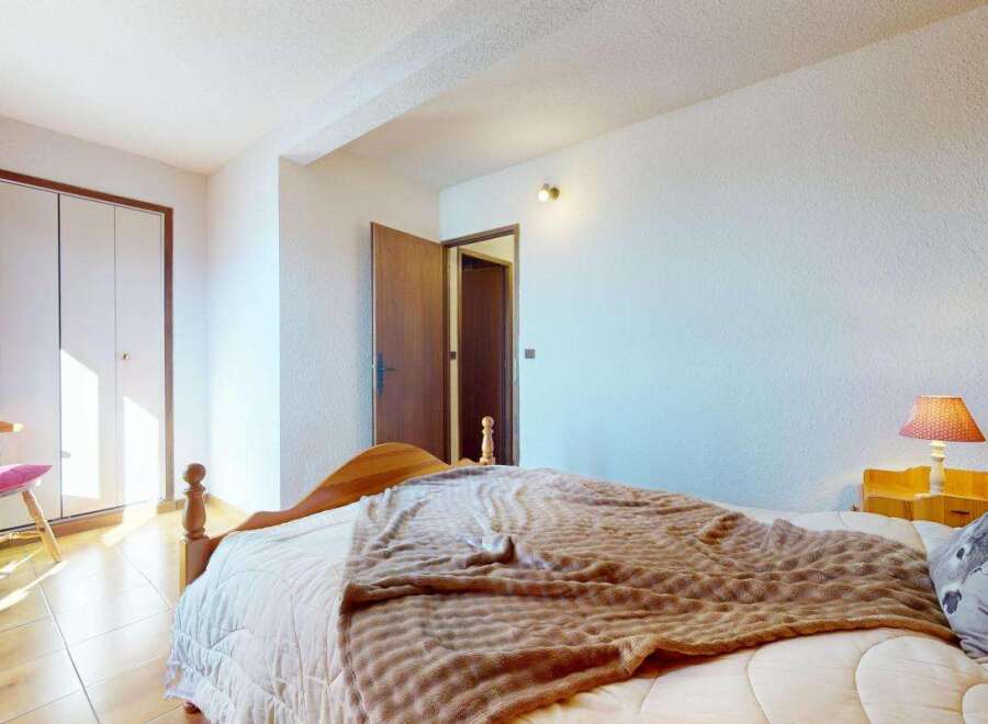 This charming bedroom features a comfortable bed adorned with a cozy brown blanket and a decorative pillow.