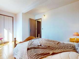 This charming bedroom features a comfortable bed adorned with a cozy brown blanket and a decorative pillow.