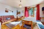 Experience cozy mountain living in this charming apartment, featuring a vibrant plaid sofa and a dining area perfect for family meals.