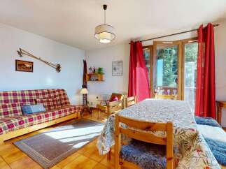 Experience cozy mountain living in this charming apartment, featuring a vibrant plaid sofa and a dining area perfect for family meals.