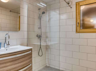 Experience modern comfort in this beautifully appointed bathroom, featuring a sleek vanity with a waterfall countertop and a spacious walk-in shower with a rainfall showerhead.