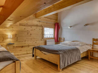 Experience cozy mountain living in this charming attic bedroom, featuring warm wooden paneling and exposed beams.