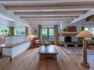 Experience cozy living in this charming mountain retreat, featuring a spacious living area with a rustic stone fireplace and exposed wooden beams.