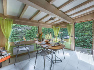 Enjoy your meals in this charming sunroom, featuring a wooden dining table and chairs perfect for intimate gatherings.