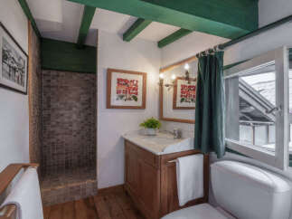 This charming bathroom features a tiled walk-in shower and a wooden vanity with a marble countertop.