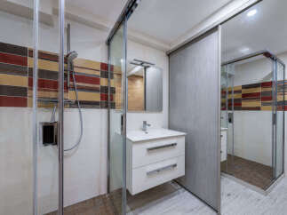 This modern bathroom features a spacious walk-in shower with a decorative tiled accent wall, offering a spa-like experience.