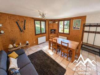 Experience cozy mountain living in this charming dining and living area, featuring warm wood paneling and ski-themed decor.