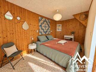 This charming bedroom features a cozy bed with a rust-colored throw and a light green duvet, complemented by a plush cream rug.