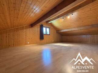 Discover this spacious attic room with beautiful wooden paneling on the walls and ceiling, creating a warm and inviting atmosphere.