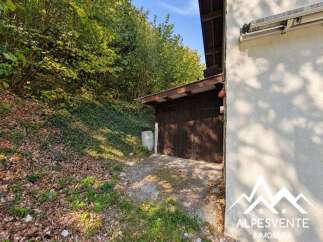 Discover this charming property featuring a rustic wooden garage nestled against a lush, green hillside.