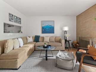 This inviting living room features a spacious sectional sofa perfect for family gatherings, complemented by a stylish glass coffee table and a cozy fireplace.