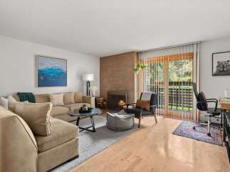 Cozy living room featuring a plush sectional sofa, a modern fireplace with a stacked wood accent, and a glass-top coffee table.