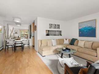 This open-concept living and dining area boasts a spacious sectional sofa perfect for gatherings, complemented by a modern glass coffee table.