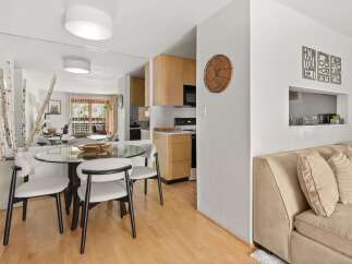 This modern dining area features a sleek glass-top dining table with four upholstered chairs, perfect for intimate meals.